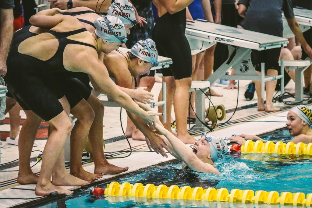 Euphoric swimmers celebrate victory at a swimming meet, showing team spirit and joy.